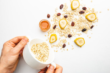 Bowl of oatmeal for porridge with ingredients banana, honey and raisins on white background, healthy breakfast every day, diet food