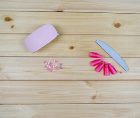 Flat lay beauty tools for manicure and pedicure on wood background. The saw is grainy for nail dressing. LED dryer mini lamp for gel. Artificial plastic tips french design for extension nails.