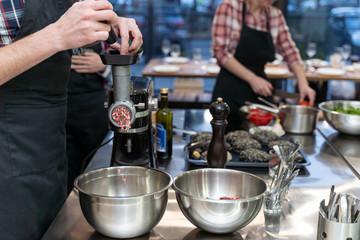 Obraz na płótnie Canvas Chef mincing raw meat with an electric grinder