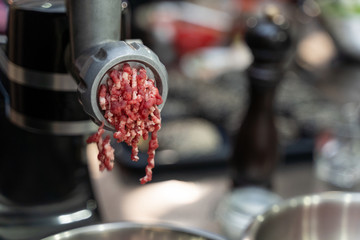 Minced beef meat coming out of a grinder