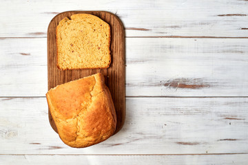 A loaf of baked homemade bread on a white wooden background.