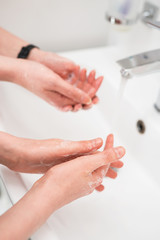 Fototapeta na wymiar Family washing hands under water tap at home. Coronavirus protection concept.