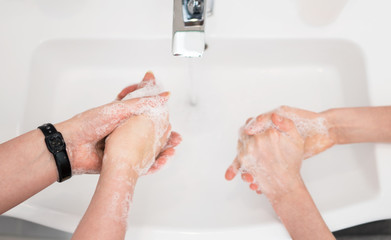 Family washing hands under water tap at home. Coronavirus protection concept.