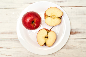Ripe red apples on a plate on a wooden background.