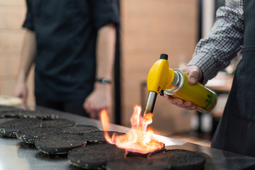 Chef using a blowtorch to crust up burger buns