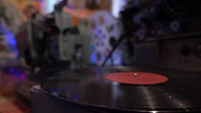 Slow motion shot of old patephone playing in dark room surrounded by cinematographic technique, grainy view
