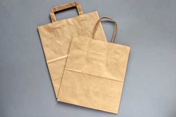 Recycled,brown,paper,shopping bag,handle, on gray background, flat lay, mockup. Two folded empty paper bag. Close-up. Selective focus. Copy space.