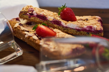 Wooden dark background of planks, white cloth, glasses with tea and homemade pie with cherries and strawberries. Delicious pastries for breakfast.