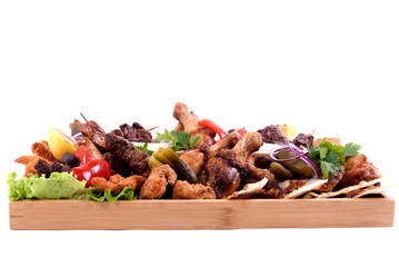 Assorted grilled sausages on a wooden board isolated.Tray with different types of sausages, meat,grilled vegetables, with different sauces on a wooden plate. to be used for restaurants, barbecues.