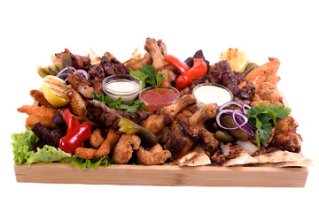 Assorted grilled sausages on a wooden board isolated.Tray with different types of sausages, meat,grilled vegetables, with different sauces on a wooden plate. to be used for restaurants, barbecues.