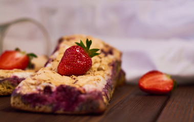 Wooden dark background of planks, white cloth, glasses with tea and homemade pie with cherries and strawberries. Delicious pastries for breakfast.