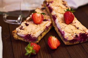 Wooden dark background of planks, white cloth, glasses with tea and homemade pie with cherries and strawberries. Delicious pastries for breakfast.