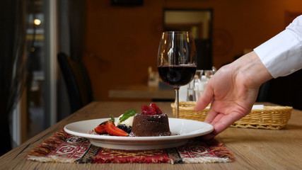 Piece of delicious cheesecake with strawberry and mint leaves on white plate. Breakfast in the cafe, morning coffee. Cappuccino and lots of desserts on the table.