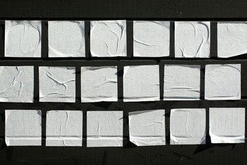 Square sheets of paper glued on a black wooden board.