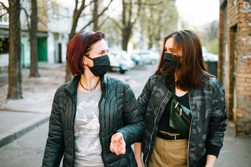 Two woman: mother and doughter walking and talking down the street in protective mask from virus (MERS) 