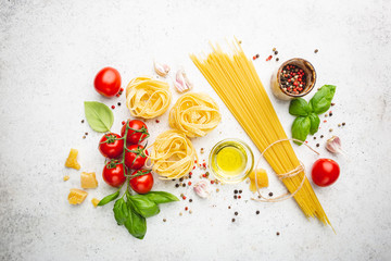 Pasta background. Several types of dry pasta with vegetables and herbs on white background. Free space for text. Top view
