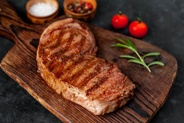 grilled beef steak with spices on a cutting board on a stone background