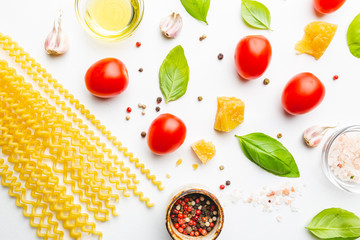 Pasta background. Several types of dry pasta with vegetables and herbs on white background. Free space for text. Top view