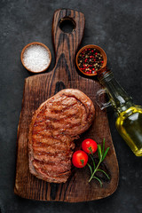 grilled beef steak with spices on a cutting board on a stone background