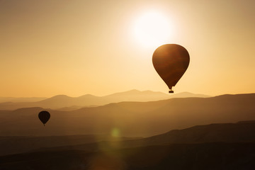 Silhouette of balloons with sunrise in background, aerial view