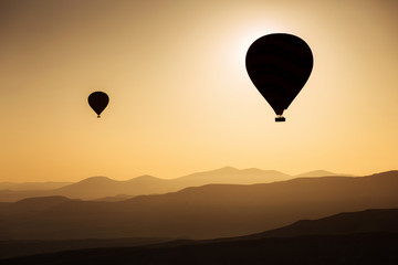 Silhouette of balloons with sunrise in background, aerial view