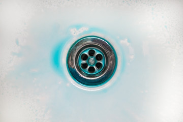 the blue mud cleaning liquid is located in the center around the drain hole. Removing dirt from the enamel surface