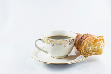 Vintage cup of coffee and piece of croissant on white background