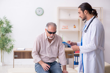Obraz premium Old blind man visiting young male doctor