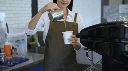 Coffee shop concept. The female waitress poured a drink from a jug into a paper cup. 4k Resolution.