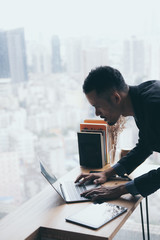 A young businessman in a black suit is working on a laptop from a private residence, working online...