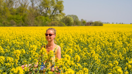 Fototapeta premium eine junge Frau sitzt in einem Rapsfeld in der Sonne