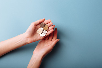 Woman's hands holding a heap of coins background, top view, with copy space