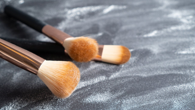 Professional makeup brush set on background with white face powder. Various makeup brushes. Fashion background.