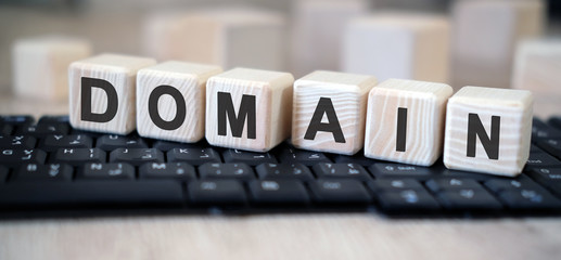 Domain - text cubes stand on a black keyboard on a wooden table