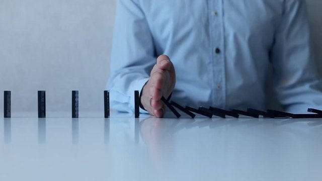 Man stops of queued up falling dominos. Social distancing and saving from spreading virus, concept.