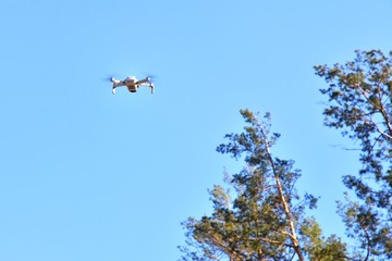 Flying drone with selective focus on blue sky background. Drone control.  Aerial surveillance. quadrocopter outdoors.