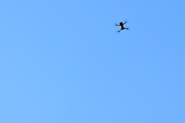 Flying drone with selective focus on blue sky background. Drone control.  Aerial surveillance. quadrocopter outdoors.