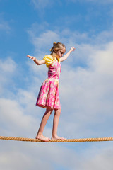 Photo art of young preteen girl on tightrope representing the process of growing up and making decisions.