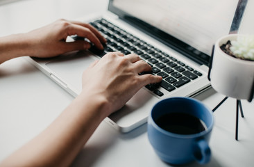 woman hands working on a laptop with a cup of coffee