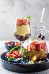 White wine sangria or punch with berries and ice in glass and pincher. Homemade refreshing fruit sangria.