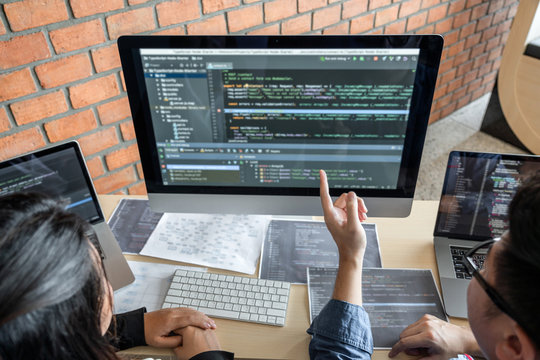 Two professional programmer cooperating and working on web site project in a software developing on desktop computer at company, codes and typing data code, Programming with HTML, PHP and javascript
