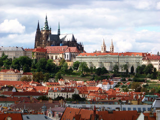 Obraz premium Wide panoramic view of the St Vitus Cathedral and Prague Castle. Multiple red rooftops on a cloudy sky background
