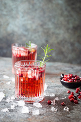 Fresh cranberry cocktail with rosemary in a glass on gray background.