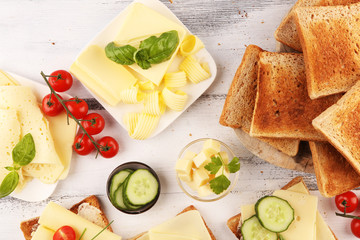 rolled slices of golden gouda cheese on a sandwich garnished with sliced cucumber and herbs. bread...