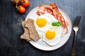 Fried eggs and bacon for breakfast on a plate, top view, copyspace