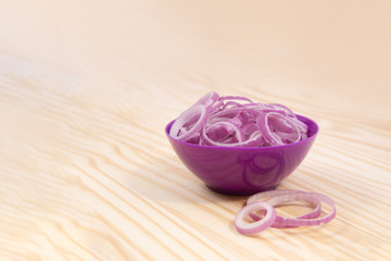 Obraz na płótnie Canvas Slices of .onion. Onion in ceramic bowl on wooden background