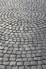 Brick cobblestone street background with rocky pavement pattern. Empty grey stone paved pattern, old town ancient street detail, abstract cobblestone pavement perspective on sunny day with no people
