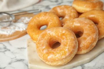 Delicious glazed donuts on marble table, closeup