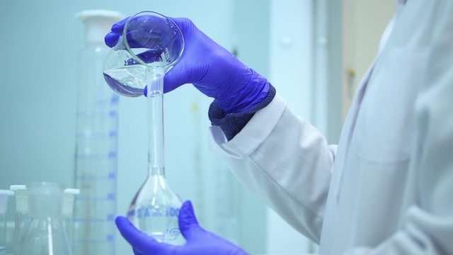 scientist mixing two clear transparent liquids in a beaker Spbd. Pouring liquid into flask using pipette. medical pharmaceutical experiment in laboratory. scientific expertise. lab equipment.