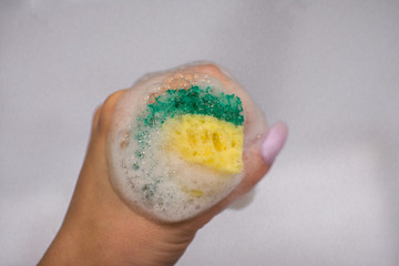 foam sponge in hand cleaning the bathroom with soap